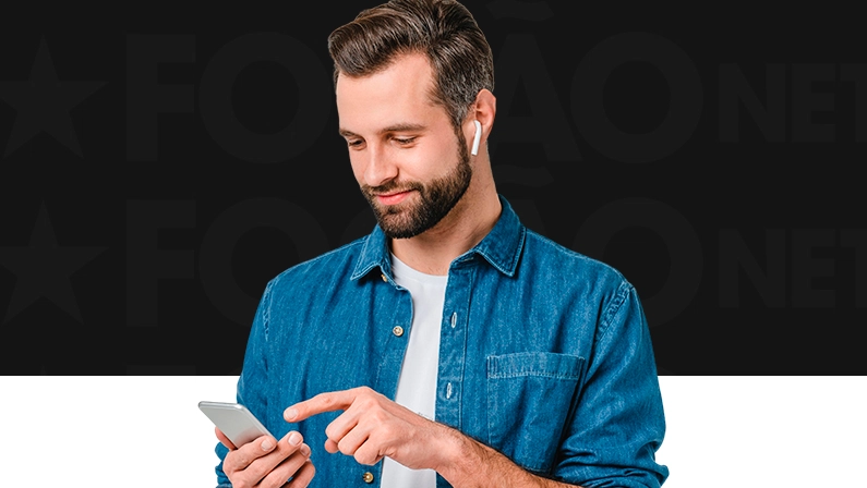 Imagem mostra homem sorrindo ao utilizar um smartphone