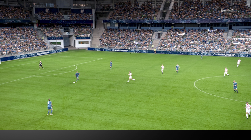 Imagem mostra uma partida de futebol vista do alto da arquibancada do estádio.